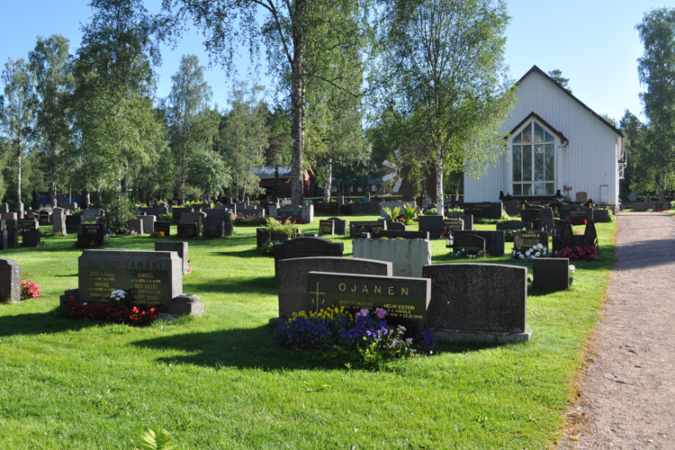 Hautakiviä Jalasjärven hautausmaalla, taustalla siunauskappeli.