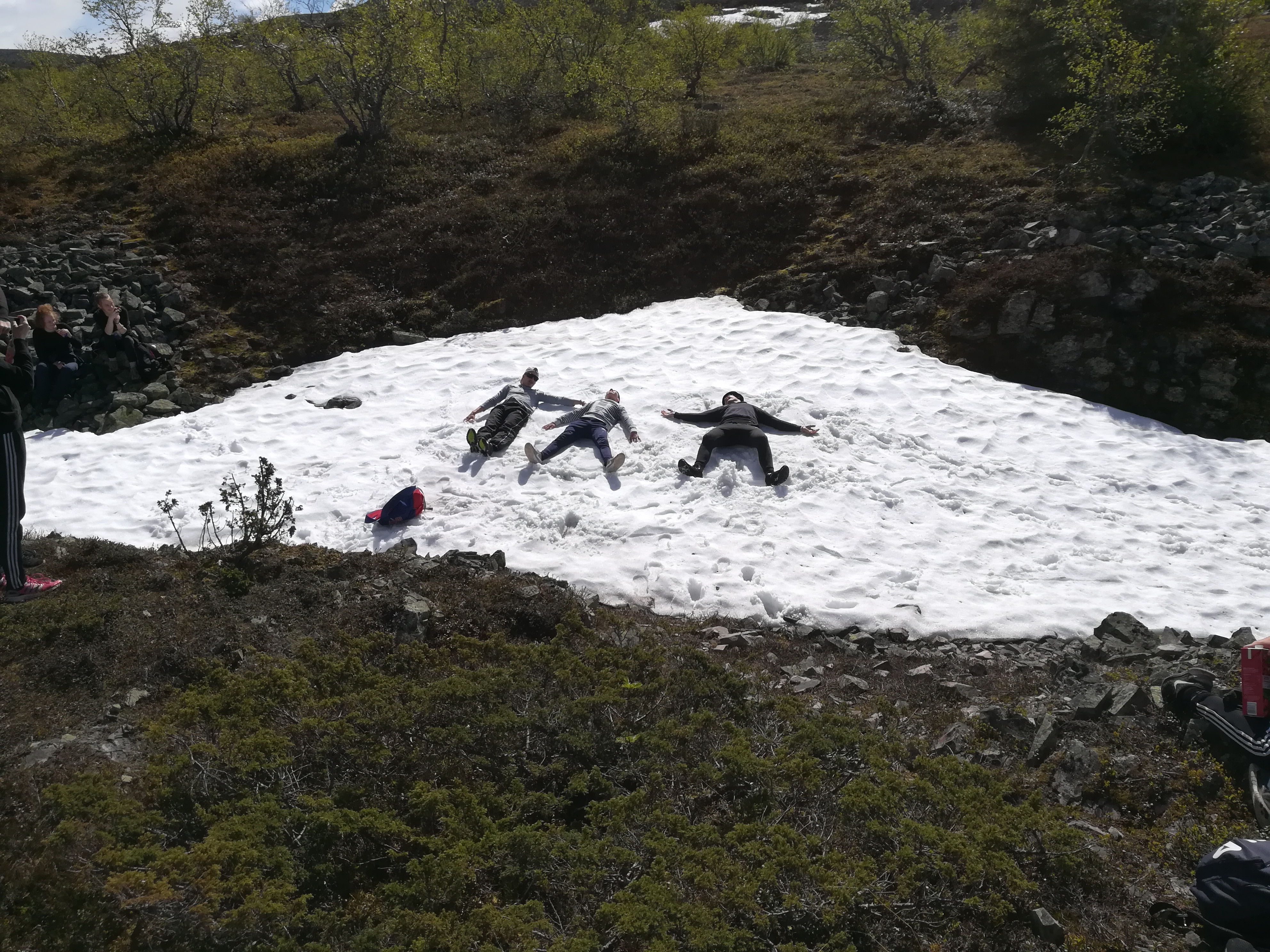 Isoskoulutus Kolme poikaa otta aurinkoa lumihangessa maaten kesäkuun Pyhätunturilla.