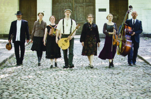 Folk-yhtyeen seitsemän muusikkoa soittimiensa kanssa vanhan kaupungin mukulakivikadulla