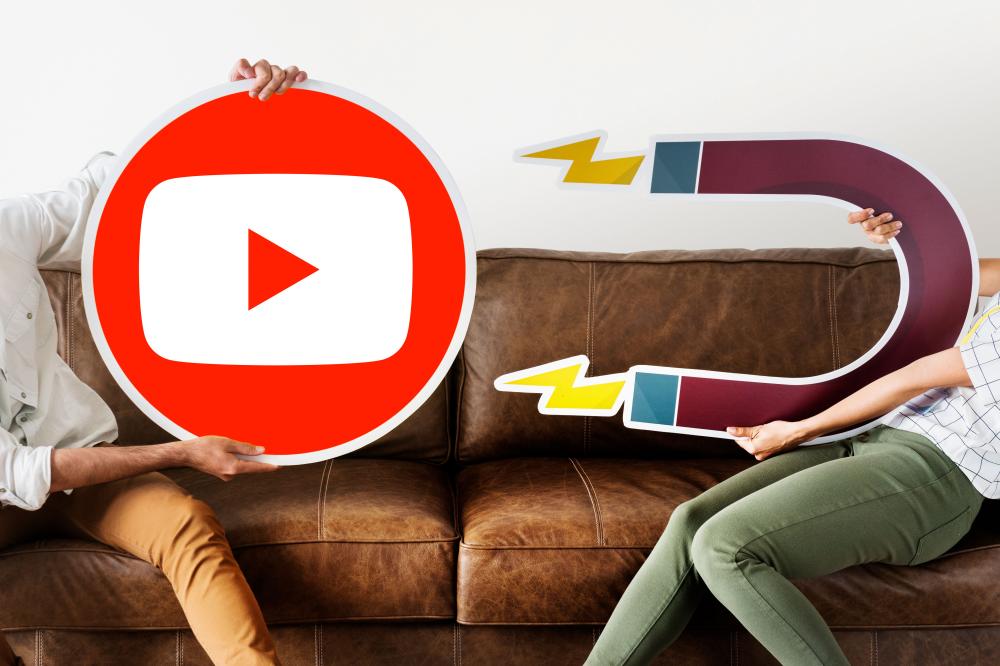 Kaksi naista. Toinen pitää kädessään isoa pahvikuvaa YouTuben logosta ja toisella on pahvikuvana magneetti.